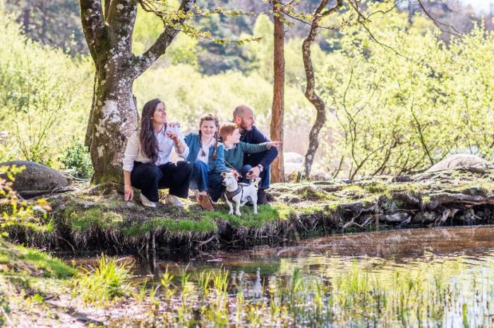 Couple avec deux enfants et un chien en bord de rivière à genou
